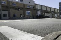 the man is riding his skateboard down the street as another man watches him walk across the road