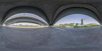 a fisheye photograph of a skateboarder doing a trick on the surface of an overpass