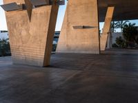 a skateboarder does a trick near a large structure and palm trees outside a building