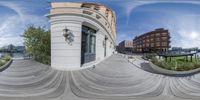 a fisheye lens shows a skateboarder doing tricks on the ground in front of an apartment building