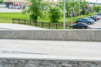 a skateboarder is doing tricks at the park, with a sidewalk below and sidewalk along the road