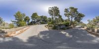 a skateboarder performing a trick down a winding road near the mountains under a blue sky