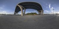 the view is looking through an upside down fisheye lens of a skateboarder riding beneath an overpass