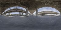 a skate boarder going up the side of a ramp under an overpass with multiple arched arches