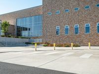 a man riding a skateboard past a big brick building with stairs on it's side