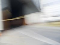 a skateboarder in motion in front of a building with a sky background and a blurred backdrop