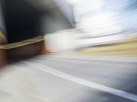 a skateboarder in motion in front of a building with a sky background and a blurred backdrop