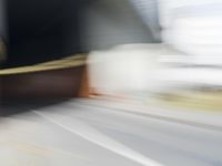 a skateboarder in motion in front of a building with a sky background and a blurred backdrop