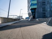 a skateboarder is going down a empty road, near a building on the edge of an urban street