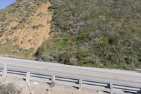 a person on a skateboard on the side of a winding road with a ramp