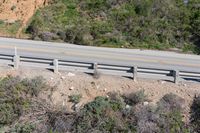 a person on a skateboard on the side of a winding road with a ramp