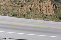 a person on a skateboard on the side of a winding road with a ramp