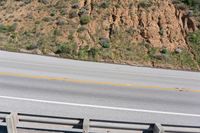 a person on a skateboard on the side of a winding road with a ramp