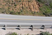 a person on a skateboard on the side of a winding road with a ramp