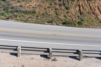 a person on a skateboard on the side of a winding road with a ramp