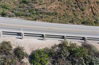 a person on a skateboard on the side of a winding road with a ramp