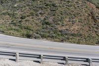 a person on a skateboard on the side of a winding road with a ramp