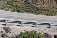 a person on a skateboard on the side of a winding road with a ramp