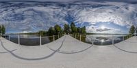 a 360 - mirror photo of skateboarders at a ramp near water and trees