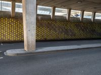 a man is skateboarding on an asphalt street in a city tunnelway near a building