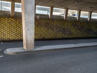 a man is skateboarding on an asphalt street in a city tunnelway near a building