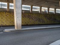 a man is skateboarding on an asphalt street in a city tunnelway near a building