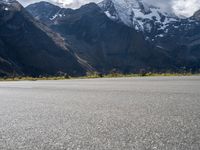 a skateboarder is riding down the road in front of snow - capped mountains