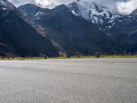 a skateboarder is riding down the road in front of snow - capped mountains