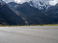 a skateboarder is riding down the road in front of snow - capped mountains