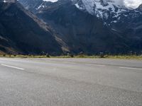 a skateboarder is riding down the road in front of snow - capped mountains