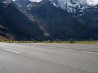 a skateboarder is riding down the road in front of snow - capped mountains