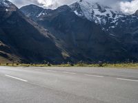 a skateboarder is riding down the road in front of snow - capped mountains