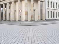 a man riding his skateboard across the middle of an outdoor plaza in front of pillars