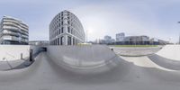 two skateboarders in a half pipe skate park with buildings behind them, both blurred