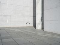 a young man riding on a skateboard across a concrete floor next to two walls