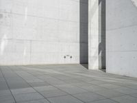 a young man riding on a skateboard across a concrete floor next to two walls