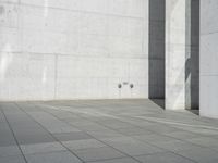 a young man riding on a skateboard across a concrete floor next to two walls