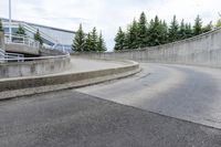 a boy skateboarding along an empty concrete road next to trees with gray and white clouds above