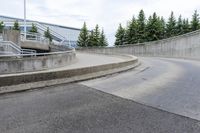 a boy skateboarding along an empty concrete road next to trees with gray and white clouds above