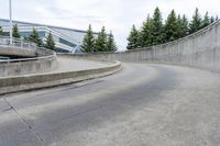 a boy skateboarding along an empty concrete road next to trees with gray and white clouds above