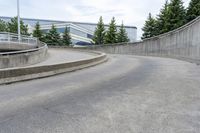 a boy skateboarding along an empty concrete road next to trees with gray and white clouds above