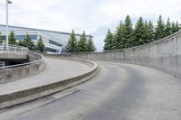 a boy skateboarding along an empty concrete road next to trees with gray and white clouds above