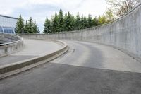 a boy skateboarding along an empty concrete road next to trees with gray and white clouds above