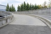 a boy skateboarding along an empty concrete road next to trees with gray and white clouds above