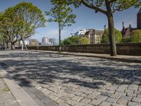 a person on a skateboard is on the brick walkway, passing other people with the city in the distance