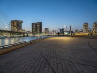 a man skateboarding on a walkway by the river with the cityscape in the background