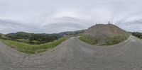 there are two skate boards going down a steep hill on a cloudy day with a person doing something