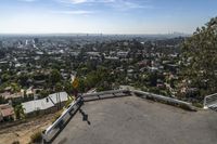 a person on skateboard going up a hill with a city view behind them on top of a mountain