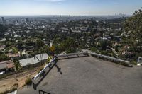 a person on skateboard going up a hill with a city view behind them on top of a mountain