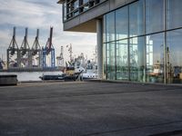 a person on a skateboard on a cement road near a large glass building and boats
